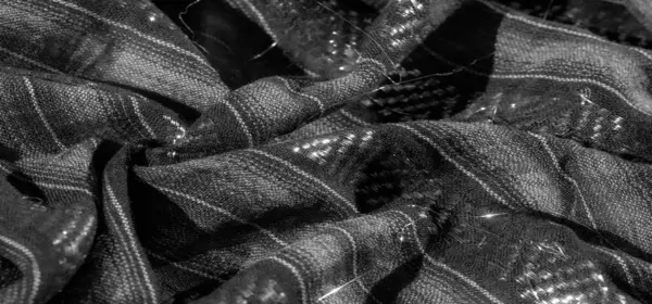 Dokuma dokusunun yakın görüntüsü ince dokuma dokuları ve yansıtıcı elementleri olan tek renkli siyah bir desen içerir. Parlak ve zarif bir görsel oluşturur..