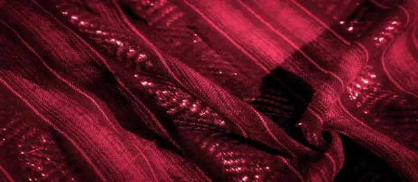 Parlak kaplamasını ve parıldayan ipliklerini gösteren kırmızı kumaşın detaylı bir yakın çekimi dokular ve desenler arasındaki etkileşim zengin niceliğini vurgulayan dinamik bir görsel deneyim yaratır.