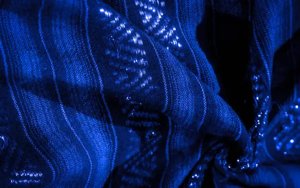 Mavi kumaşın parıldayan yüzeyi, büyüleyici desenlerdeki ışığı yansıtır. Sıkıca örülmüş doku, ışıltı ve yapı arasında zarif bir denge yaratır.,