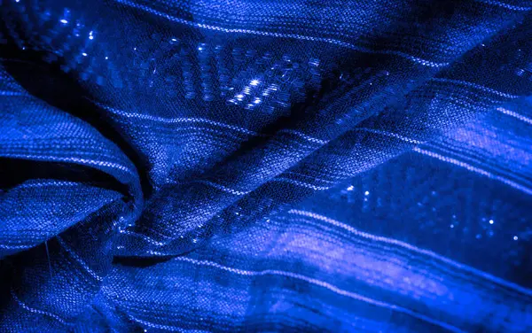 Karmaşık dokuma desenleri ve yansıtıcı ipliklerle donanmanın mavi kumaşının bulanık bir yakın çekimi büyüleyici bir doku yaratıyor ve kıvrımların derinliğini vurguluyor.