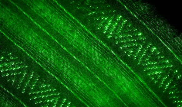 Bulanık, yeşil kumaş parlayan bir parıltıyla soyut desenlere sahip, görsel olarak büyüleyici bir doku yaratıyor. İç içe geçmiş kumaş ve ışık yansımaları sanatsal ve modern bir his uyandırıyor..