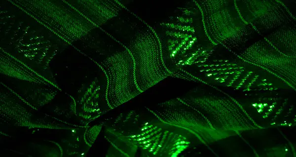 Parlak yeşil dokuların parlayan ipliklerle iç içe geçtiği görsel olarak çekici bir kumaş sahnesi. Fotoğraf, hafif aksanlı katmanlı ve detaylı yapıları yakalıyor..