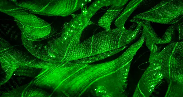Yeşil kumaşa dokunmuş liflerin yumuşak parıltısını bulanıklaştırır. Karmaşık dokunun üzerinde soyut bir ışık dansı yaratır. Tasarım, kumaşın kıvrımlarında dalgalanan parıldayan çizgileri ortaya çıkarır.
