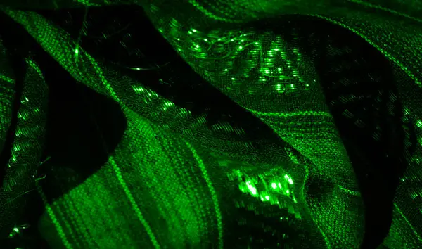 Parlak dokusu ve dokuması olan yeşil kumaş bulanıklığı. Işık karmaşık kumaş deseninden yansıyarak katmanlarda ve katmanlarda derinlik ve detay oluşturur..