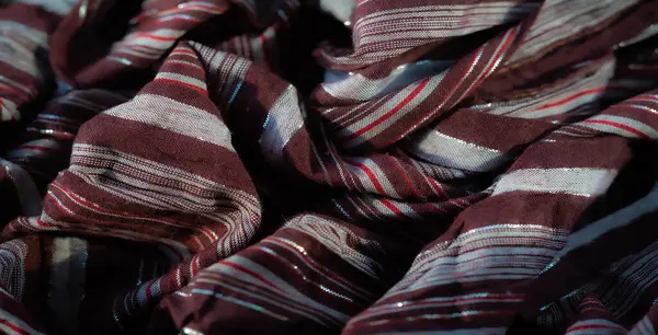 Koyu kırmızı ve beyaz çizgilerle parıldayan gümüş detaylar içeren desenli bir bordo kumaş. Yumuşak kıvrımlar ve zengin tonlar moda için şık bir seçim.