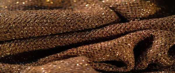 Koyu renk parıltılı ve parlak renklerle dokulu bir kumaşın makro görüntüsü. Görüntü karmaşık dokumayı ve parlak kıvrımları gösteriyor, zarif, lüks bir tekstil yüzeyi oluşturuyor..