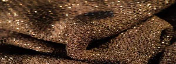 Koyu renkli, parlak bir kumaşın bulanıklığı, parlak renklerle dokunmuş ince bir dokuyu sergiliyor. Yumuşak kıvrımlar, materyalde zengin bir derinlik ve lüks hissi yaratır..