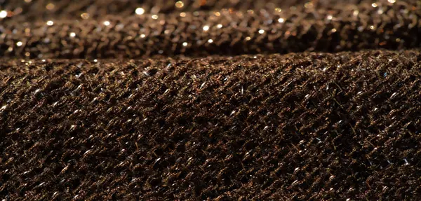 Koyu renkli, parlak bir kumaşın bulanıklığı, parlak renklerle dokunmuş ince bir dokuyu sergiliyor. Yumuşak kıvrımlar, materyalde zengin bir derinlik ve lüks hissi yaratır..