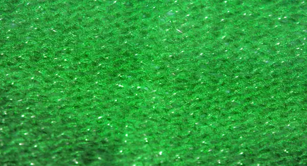 Kumaş, etrafındaki ışığı yansıtan parıltılı bir yüzeyle güçlendirilmiş parlak yeşil bir renk sergiliyor. Dokuma dokusu ve ince kıvrımlar canlı ve lüks bir görsel etki yaratır..