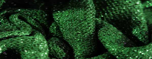 Işıldayan beneklerle süslenmiş canlı yeşil kumaş bulanıklığı, yumuşak odaklı dokulu bir yüzey gösteriyor, arka plan veya materyal odaklı projeler için mükemmel