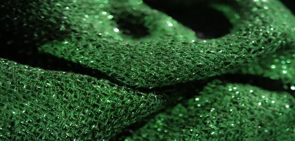 Parlak bir dokusu ve karmaşık dokuması olan yeşil parıltılı kumaşın bulanık görüntüsü. Parlak, parlak bir tekstil etkisi yaratmak için ışık yansıtan bir madde..