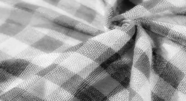 Görüntü. Gri ve beyaz dokuma dokuması olan kareli kumaşın yakın çekim görüntüsü. Kumaşlar katlanır ve ışık yansımaları gölgelerin dinamik etkileşimini yaratır.,