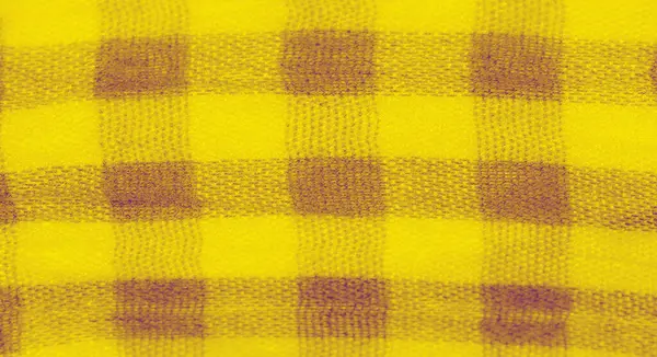 Yumuşak kıvrımları ve damalı desenleri olan dokulu sarı bir kumaşın bulanıklığı. Kumaş, ışık ve gölgenin ince zıtlıklarını gösterir ve tasarımda dinamik bir akış yaratır..