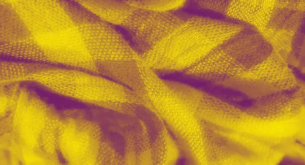 Sarı ve mor kareli kumaş bulanıklığı, yumuşak kıvrımlara ve dokulu dokumaya odaklanmış. Parlak sarı ve koyu mor arasındaki zıtlık dinamik bir görsel etki yaratır..