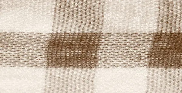 Katlanmış ve toplanmış bej ve kahverengi damalı kumaşın bulanıklığı. Kumaşın yumuşak ve dokulu bir görüntüsü var. Sade ve sade cazibesini vurguluyor..