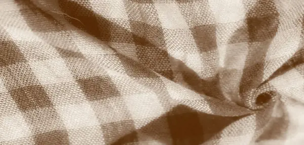 Detaylı dokuma desenli damalı bej kumaşın bulanık görüntüsü. Kumaş doğal olarak bükülür ve kıvrılır, yumuşak gölgeler bırakır ve yüzeyine ışık tutar, derinliği arttırır..