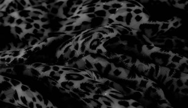 Belirsiz bir yüzeyde koyu soyut desenleri olan yüksek kontrastlı bulanık kumaş. Karmaşık detaylar ve derinlik gösteriyor. Siyah şekiller yumuşak, neredeyse şeffaf arkaplanda göze çarpar..