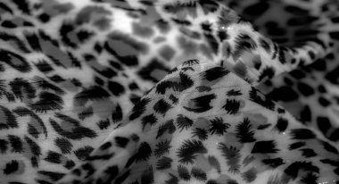 Yumuşak kumaş üzerinde siyah ve gri soyut desenler, görsel olarak dinamik ve dokulu bir görünüm yaratıyor. Arkaplan, tekstil tasarımı veya dekoratif projeler için ideal.