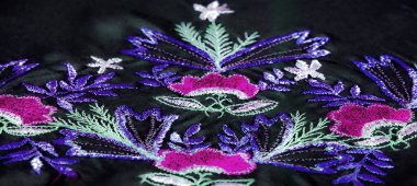 Kumaşın bulanık kıvrımları neon rengi mor, yumuşak pembe ve yeşil aksanlı çiçek desenleri gösteriyor. Nakış kumaşa derinlik ve dokunsal bir öğe ekler..