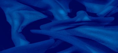 Görüntü. Mavi kumaşın soyut bir yakın çekimi, karmaşık kıvrımlar ve ışık oyunlarını, zarafet ve çok yönlülüğü, modern arka planlar ve tekstil sanatı için uygunluğu gösteriyor.