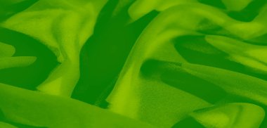 Görüntü, canlı yeşil kumaş bir dizi yumuşak, akışkan kıvrımlar halinde açılır ve nazik dalgalar izlenimi yaratır. Yumuşak, kadifemsi dokusu, maddenin lüks kalitesini vurgular..