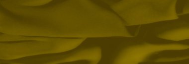 Pürüzsüz ve desenli yüzeylerin karışımından oluşan sarı-yeşil kumaş katmanlarının bulanık tasviri. Yumuşak ışık, yumuşak kıvrımları vurgular, barışçıl bir ortam yaratır.