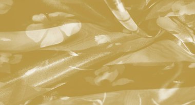 Zarif çiçek aksanlı yumuşak sarı kumaş bulanıklığı. Sıcaklık ve zarafet saçıyor. Katmanlı, akışkan kıvrımlar zarif ve sanatsal bir arkaplan için ideal bir görünüm yaratıyor..