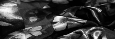 Tek renkli çiçekli kumaşın bulanıklığı. Narin taç yapraklı kumaşlar, şeffaf ve katıksız şeritler boyunca birleşmiş. Kalıplar gri tonda ince ve karmaşık bir cazibe sunuyor..