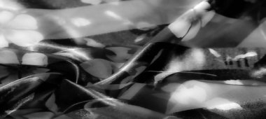 Gri tonlu kumaştaki narin çiçek desenleri hafif bir ışık ve gölge etkileşimi sergiliyor ve sakin, minimalist estetik bir arka plan oluşturuyor..