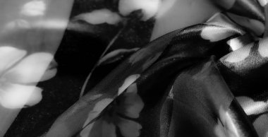 Çiçek desenli gri pullu bir kumaşın hassas, yumuşak bir odak noktası vardır, karmaşık desenleri vurgular ve şeffaf ve mat katmanlar arasında değişen derinliği rafine bir etki için.