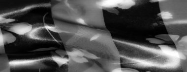 Çiçek desenli gri pullu bir kumaşın hassas, yumuşak bir odak noktası vardır, karmaşık desenleri vurgular ve şeffaf ve mat katmanlar arasında değişen derinliği rafine bir etki için.