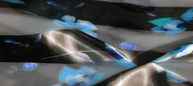 Yumuşak, akışkan kumaştan bulanık mavi ve siyah tonlarda ince çiçek desenleri. Nazik parıltı karmaşık detayları vurguluyor ve kumaşa derinlik katıyor..