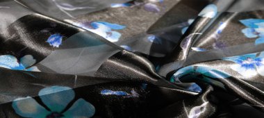 Görüntü: Bu desenli kumaş, mavi çiçeklerle akan çizgileri sergiler, katmanların şeffaflığı ve derinliğini harmanlarken, yansımalar maddedeki yumuşak bir parıltıyı vurgular.