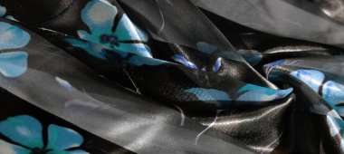 Uçuşan şeffaf kumaş katmanları mavi çiçek desenlerini koyu, pırıl pırıl bir arka planla birleştirerek yumuşak, romantik bir his yaratıyor..