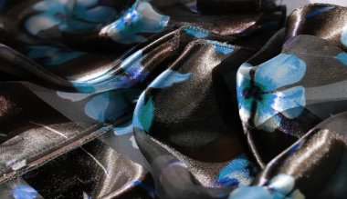 Parlak mavi çiçeklerle süslenmiş koyu ve açık renk çizgili kumaş üzerinde bulanık bir etki. Kumaşlar çiçek tasarımına doku ve derinlik katıyor. .