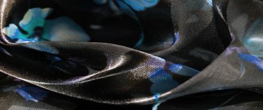 Şeffaf, parlak bir materyal üzerinde mavi ve lavanta çiçeklerinin hassas bir karışımı olan katmanlı çiçekli bulanık kumaş yumuşak bir ışık, gölge ve zengin doku etkileşimi yaratır..