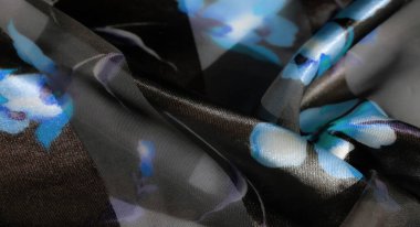 Bulanık. Saf siyah kumaş ve canlı mavi çiçek aksanlarının zarif bir karışımı. Her kıvrımında yumuşak bir parıltı olan ahenkli ve ruhani bir desen oluşturuyor..