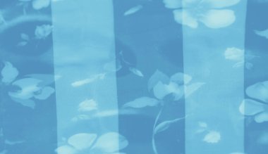 Akan dokular ve narin çiçek elementleri içeren mavi kumaş bulanıklığı, rafine ve nazik bir fon sağlayan katmanlı katmanlı katmanlı bir estetik sunuyor..