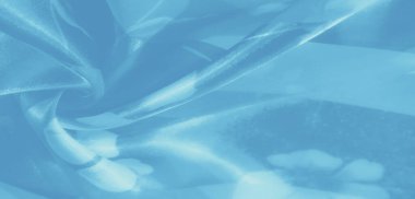 Açık mavi kumaşlı, ince çiçekli bulanık kumaş. Akan kumaş kıvrımları ve yumuşak ışıklandırma zarif bir dekor teması için mükemmel, sakin bir etki yaratır..