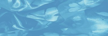 İlahi mavi kumaştan bulanık, kumaşın ipeksi kıvrımlarını ve pürüzsüz dokusunu vurgulayan yumuşak, parıldayan bir ışıkta örülmüş çiçek desenleri..