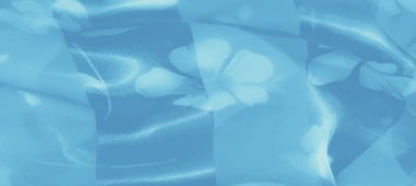 Yumuşak çiçek desenleri ve parıldayan dokularıyla narin mavi kumaş bulanıklığı. Kumaşlar nazikçe katlanır ve ışık yansımaları dingin, havadar bir his yaratır..