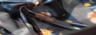 Görüntü. Kumaş, koyu ve şeffaf çizgiler üzerinde narin turuncu ve sarı çiçekleri ön plana çıkarıyor. Işıldayan kıvrımlar ve yumuşak dokular zarif bir zemin sunuyor, çiçekli güzellikler sergiliyor..