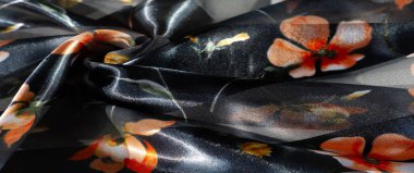 Görüntü. Zengin dokulu kumaşlarda, yumuşak, ışıltılı bir arka planda turuncu ve sarı çiçek desenleri sergilenir. Koyu ve şeffaf çizgiler derinlik ve katman hissi verir..