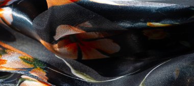 Yumuşak, pürüzsüz kumaştan oluşan bulanık, parlak turuncu ve sarı çiçek aksanlı koyu mavi bir arkaplan. Parlak parıltı onun lüks ve zarif görünümünü arttırır..