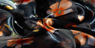 Koyu, parıltılı bir arka planda turuncu çiçek desenli saf kumaşın bulanık görüntüsü. Yumuşak kıvrımlar ve şeffaflık hassas, katmanlı bir etki yaratarak derinlik ve hareket ekliyor..