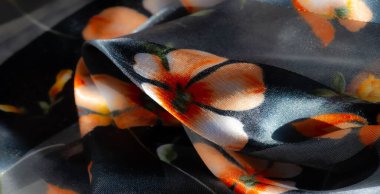 Şeffaf çiçek desenli bulanık kumaş, koyu arkaplanda canlı turuncu çiçekler, karmaşık bir ışık ve doku oyunu sunuyor, nazik kıvrımlarla vurgulanıyor ve parıldayan bir kalite.