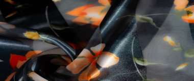 Bulanık ışık yayan kumaş. Parlayan koyu arkaplanda koyu turuncu çiçek desenleri var. Hafif ışık yansımaları ve yumuşak kıvrımlarla sıcaklık ve karmaşıklık yayıyor..