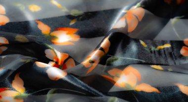 Bulanık ışık yayan kumaş. Parlayan koyu arkaplanda koyu turuncu çiçek desenleri var. Hafif ışık yansımaları ve yumuşak kıvrımlarla sıcaklık ve karmaşıklık yayıyor..