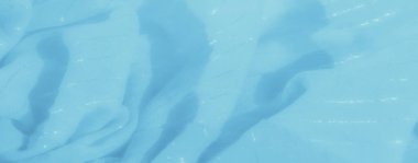 Pürüzsüz, açık mavi kumaşın bulanık görüntüsü, karmaşık kıvrımları yakalıyor ve narin, sakin bir görünüme sahip, sakin ve sanatsal bir arka plan için mükemmel bir ışık parıltısı yaratıyor..