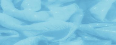 Yumuşak, parlak çizgileri ve narin dokusu olan açık mavi kumaş bulanıklığı. Kumaşlar kıvrılır ve pürüzsüz yüzey barışçıl, pastel renkli bir sahneyi çağrıştırır..